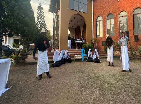 Participants in white robes performing outside the church during Hymn Carol Night