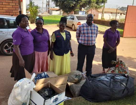 Church members standing beside bags and household items collected for people in need